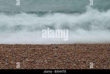 Eine Welle auf dem Kiesstrand mit einer langen Verschlusszeit aufgenommen. Stockfoto