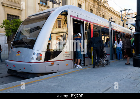 Moderne Straße / Straße tram / Straßenbahn an einer Haltestelle zu sammeln, begeben Sie sich & aussteigen der Passagiere in Sevilla / Sevilla, Andalusien. Spanien. Stockfoto