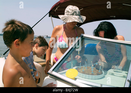 Freunde und Familie Kerzen auf Kuchen zum Geburtstag von neun Jahre alten Jungen auf einem Boot, Biscarrosse, Frankreich. Stockfoto