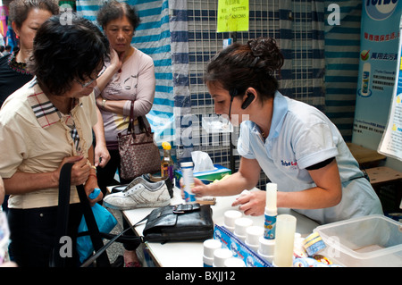 Verkäufer demonstrieren ihr Leder Reinigungsmittel bei der Ladies' Market, Mongkok, Kowloon, Hong Kong, China Stockfoto