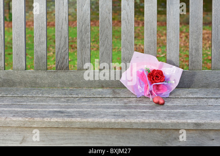 Kleine Blume Blumenstrauß ruht auf einer hölzernen Parkbank Stockfoto