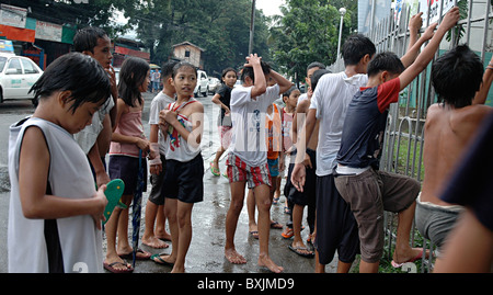 Kinder spielen nach Regenschauer in Cebu city Stockfoto