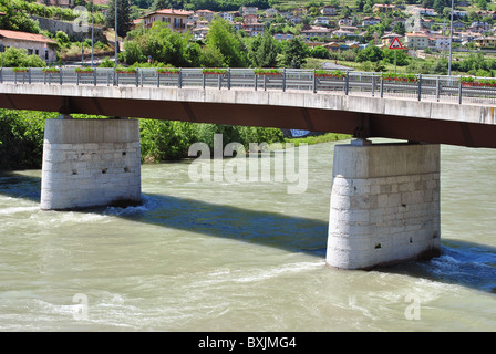 Etsch-Mündung mit frischem Wasser in Trentino Alto Adige und Hintergrund Wald und Wohnhäuser Stockfoto