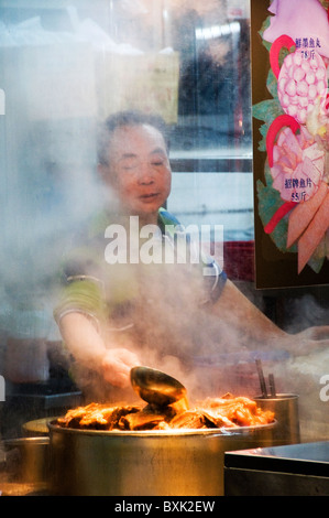 Asiatischer Mann, Zubereitung von Speisen im freien Stall auf Stadtstraße in der Innenstadt von Hongkong China Stockfoto