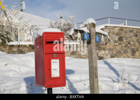 Isle of Anglesey Wales UK Dezember rote Post Box und Küstenweg Zeichen im Schnee nach ungewöhnlich starker Schneefall bedeckt Stockfoto