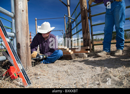 Rancher reparieren Tor auf Rinder Rutsche auf Rinderfarm Stockfoto