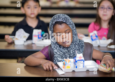 Grundschule Mädchen und Jungen zu Mittag essen und interagieren Sie mit Kommilitonen an der Buche Elementary School in Manchester NH Stockfoto