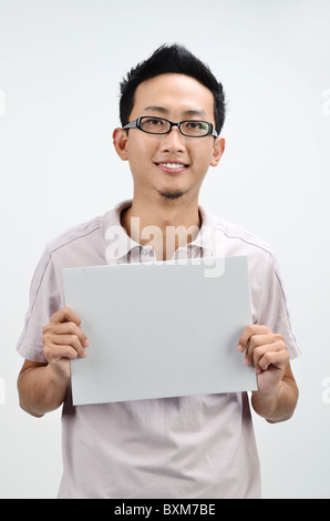 Lässige asiatischen Mann eine graue leere Karte anzeigen Stockfoto