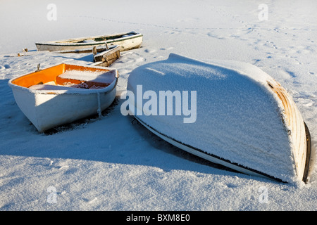 Kleine Ruderboote, bedeckt mit Schnee und Raureif am Rand von einem Bootfahren Teich, Schottland Stockfoto