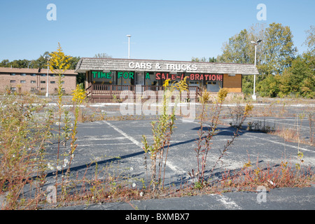 Verlassene Pkw- und LKW-Händler Baulücke mit Unkraut. Schild steht Zeit für einen Verkauf ein Bration. Stockfoto