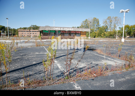 Verlassene Pkw- und LKW-Händler Baulücke mit Unkraut. Schild steht Zeit für einen Verkauf ein Bration. Stockfoto