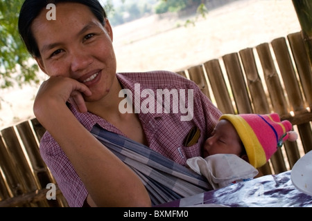 Eine ethnische Lahu Frau hält ihr Neugeborenes und lächelnd in Ban Mae Han Dorf Thailand. Stockfoto