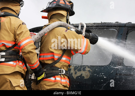 Feuerwehrleute auf einem Neuanschluß Löschangriff ein Auto Stockfoto