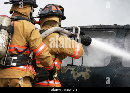 Feuerwehrleute auf einem Neuanschluß Löschangriff ein Auto Stockfoto