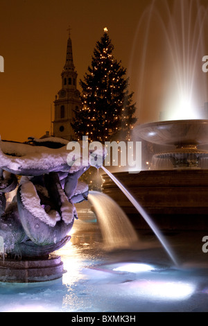 Schnee und Eis überkrustet Brunnen auf dem Londoner Trafalgar Square mit dem berühmten Weihnachtsbaum. Stockfoto