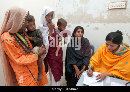 Pakistan nach der Flut. Arzt Sahira Bano untersucht einen Patienten beobachtet von ihrer Familie Stockfoto