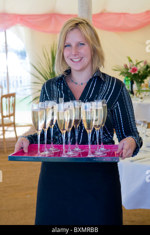 Junge glücklich aussehende Kellnerin mit einem Tablett Sektgläser Stockfoto