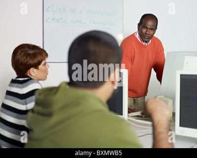 Computer-Klasse mit hispanic Kursteilnehmer Frage zu indischen Lehrer. Horizontale Form, Fokus auf Hintergrund Stockfoto