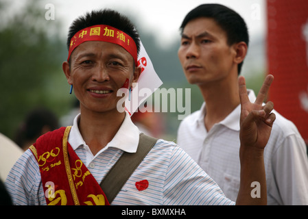 Chinesischer Mann gibt Friedenszeichen während der Parade vor den Olympischen Spielen, Peking, China Stockfoto