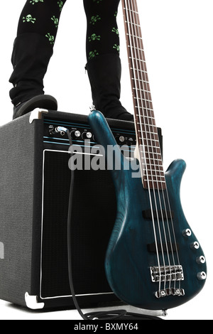 Amp und 5 String Bassgitarre in weiß mit Frau Stiefel Beinen stehend auf Amp. Stockfoto