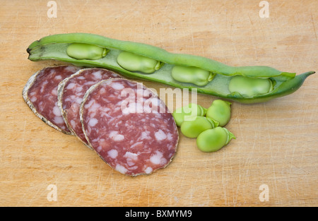 Drei Salami-Scheiben mit Bohnen auf einem Holz Schneidebrett Stockfoto