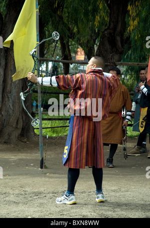 Ein Bogenschütze tragen Tracht (außer Schuhe) Ziel nimmt an einem Wettbewerb des Bogenschießens, Nationalsport Bhutans, Paro, Bhutan Stockfoto