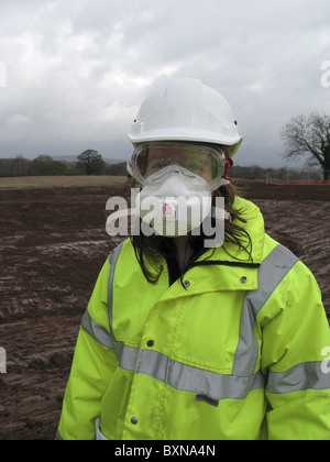 Junge Dame Bauingenieur tragen volle Schutzausrüstung gegen Kalk auf UK-Baustelle. Stockfoto