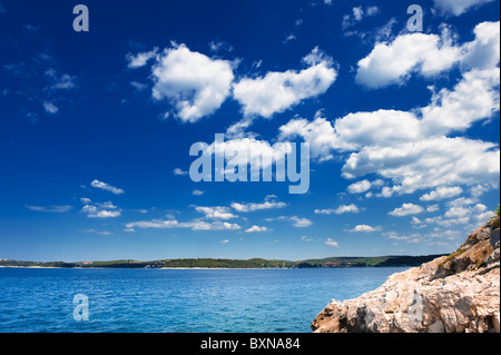 Adria Küste unter blauem Himmel. Steiniger Strand Rovinj - beliebtes Touristenziel an der kroatischen Küste. Stockfoto