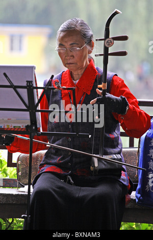 Chinesische Frau spielt traditionelle Saiteninstrument in Kunming Park, China Stockfoto