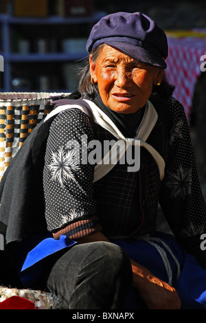 Naxi Frau sitzend auf Straße, Lijiang, Provinz Yunnan, China Stockfoto