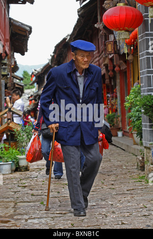 Älterer Herr, der zu Fuß gepflasterten Gassen von Lijiang, Provinz Yunnan, China Stockfoto