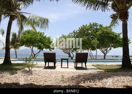 Zwei leere Stühle sitzen durch einen Pool im Spa am Meer auf einer Insel Strandresort and Spa. Stockfoto