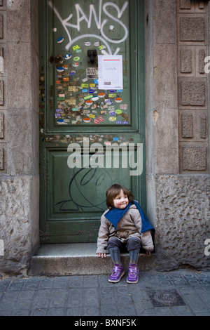 zwei Jahre alter Junge sitzt im Eingang zum Gebäude Stockfoto