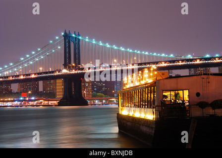 New York City Manhattan Bridge mit Schiff in der Nacht. Manhattan Brücke verbindet Manhattan und Brooklyn. Stockfoto