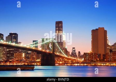 New York City Manhattan Bridge über den Hudson River mit Skyline nach Sonnenuntergang Nachtansicht mit Lichtern beleuchtet von Brookl betrachtet Stockfoto