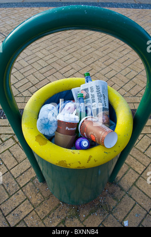 Railway Station Plattform Abfallbehälter voll mit Wertstoffen, Pappbecher, Plastikflaschen und Zeitung. Stockfoto