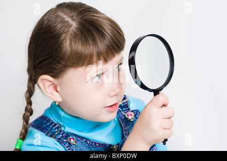 Kleines Mädchen hält aussehende Glas in der hand und beobachtete durch es in Nahaufnahme Stockfoto