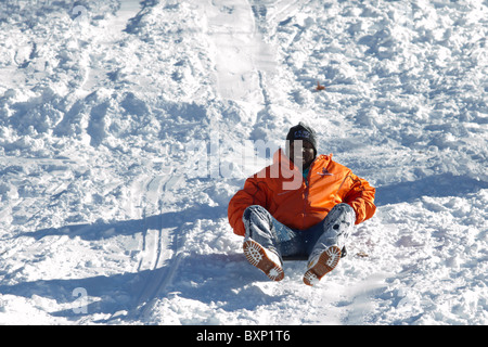 Ein Mann kommt hinunter einen Hügel im Riverside Park auf seinen Schlitten am Tag nach ein späten Dezember Schneesturm New York City decken fliegen Stockfoto