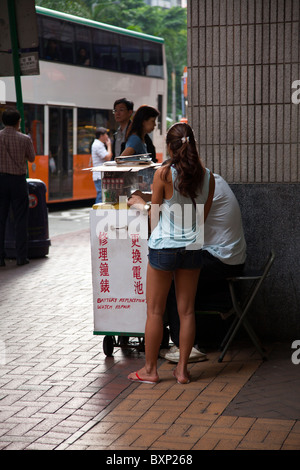 Die berühmt-berüchtigten Lockhart Road, Hong Kong, China, Suzi Wong Ruhm. Junge Mädchen, das Uhren repariert an der Straßenecke Stockfoto