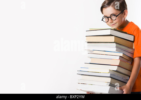 Foto von clever Vorschulkind halten schwere Stapel Bücher und seine Spitze Kinn berühren Stockfoto