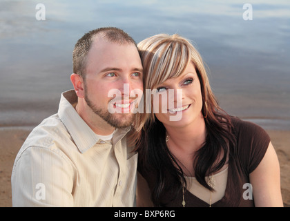 junge Brautpaar sitzt in der Nähe zusammen einer See-Nahaufnahme Stockfoto