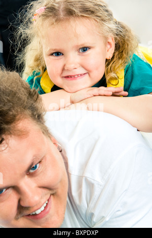 Nahaufnahme der kleinen glücklichen Mädchen auf ihren Vater zurück Blick in die Kamera Lächeln Stockfoto
