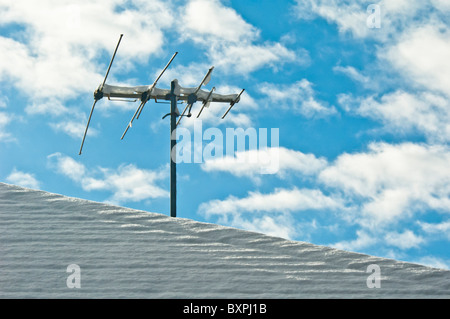 TV-Antenne auf einem verschneiten Dach Stockfoto