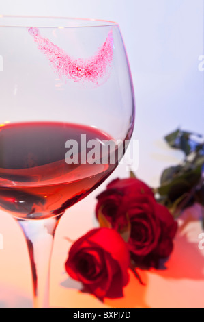 Romantik wird in einem Bild eines Weinglases mit Lippenstift Marken und rote Rosen angedeutet. Stockfoto