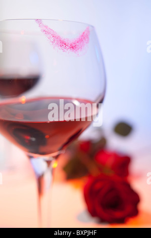 Romantik wird in einem Bild eines Weinglases mit Lippenstift Marken und rote Rosen angedeutet. Stockfoto