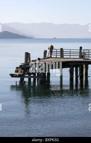 Ein einsamer Fischer steht am Ende ein Holzsteg in Lake Wakatipu in den frühen Morgenstunden Stockfoto