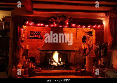 Ein Inglenook Kamin in einem englischen Landhaus an Weihnachten dekoriert. Stockfoto