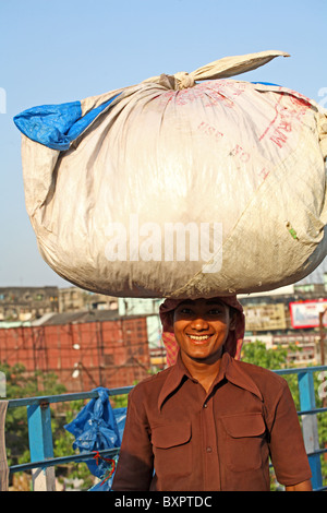 Lächelnd indischen Mann tragen Gewicht auf Kopf, Kalkutta Indien Stockfoto