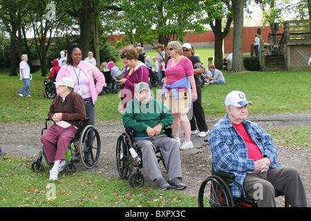 Drei ältere Männer Teilnehmer im Rollstuhl. Mit Frauen-Betreuer. Alzheimer Speicher zu Fuß. Zu Fuß zum Ende Alzheimer. Stockfoto