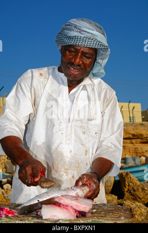 Dunkel-enthäutete Fischhändler schneiden frischer Fisch auf einem freien Markt Abwürgen, Sur, Sultanat von Oman Stockfoto